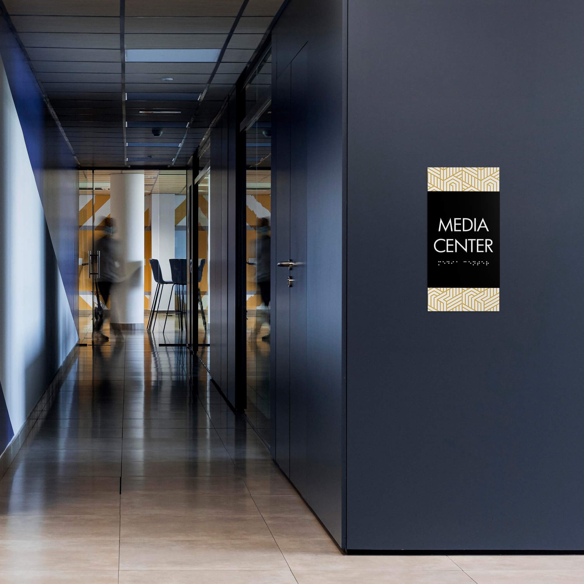 A vertical 2-layer ADA sign for a media center with a black foreground and modern geometric background