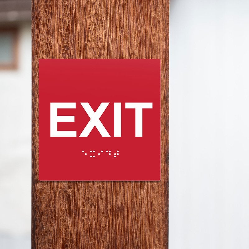 A red ADA exit sign on a pole