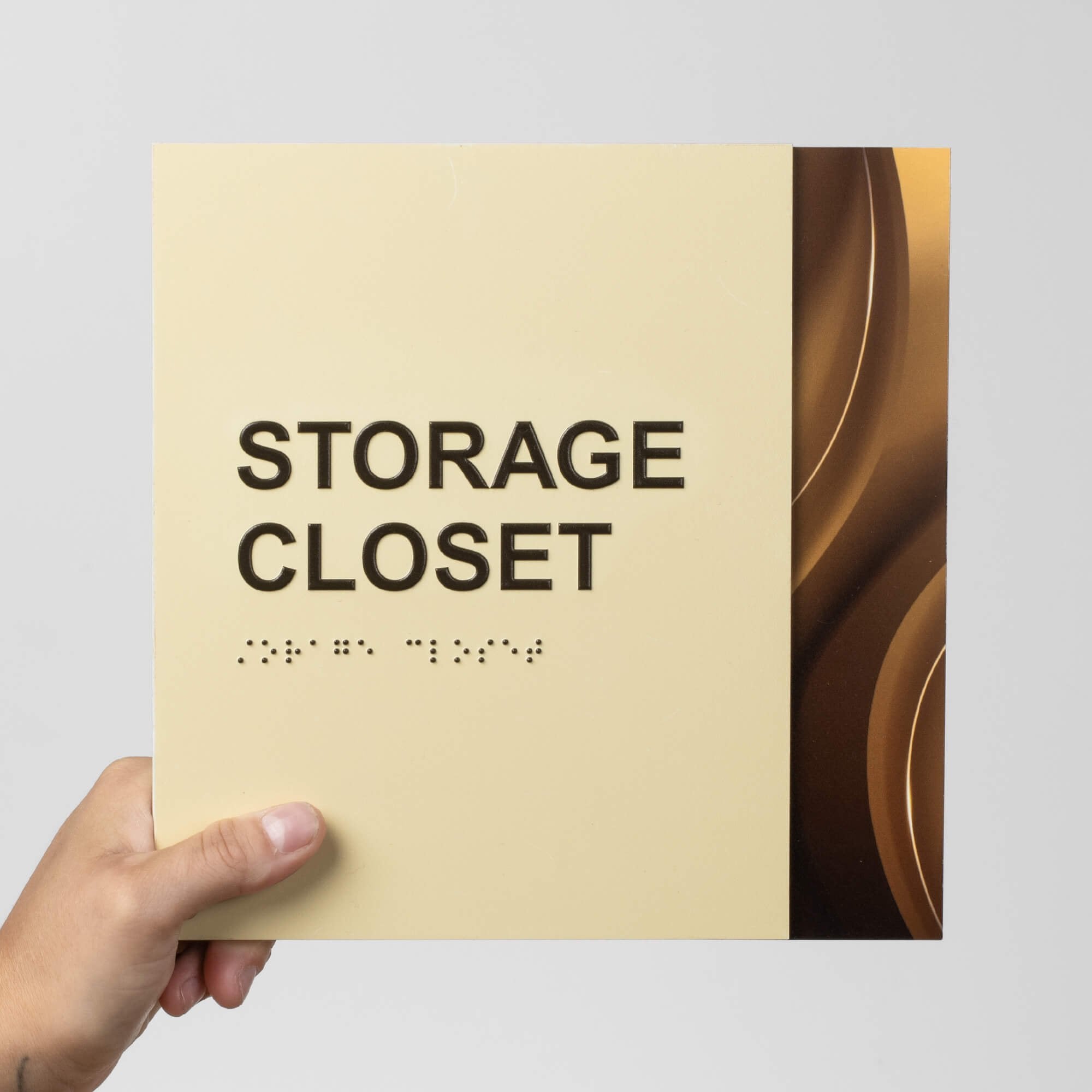 A person holding a two-tone layered ADA sign that says "storage closet" A person holding a two-tone layered ADA sign that says "storage closet"