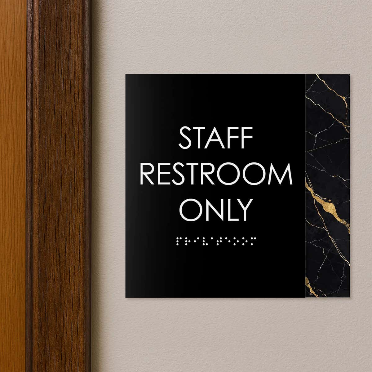 A modern layered ADA sign for a staff restroom hung next to a doorway