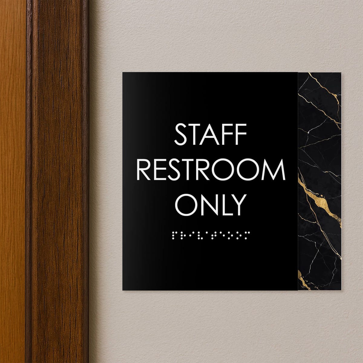 A modern layered ADA sign for a staff restroom hung next to a doorway