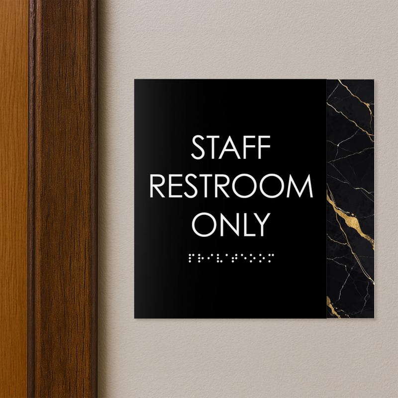A modern layered ADA sign for a staff restroom hung next to a doorway