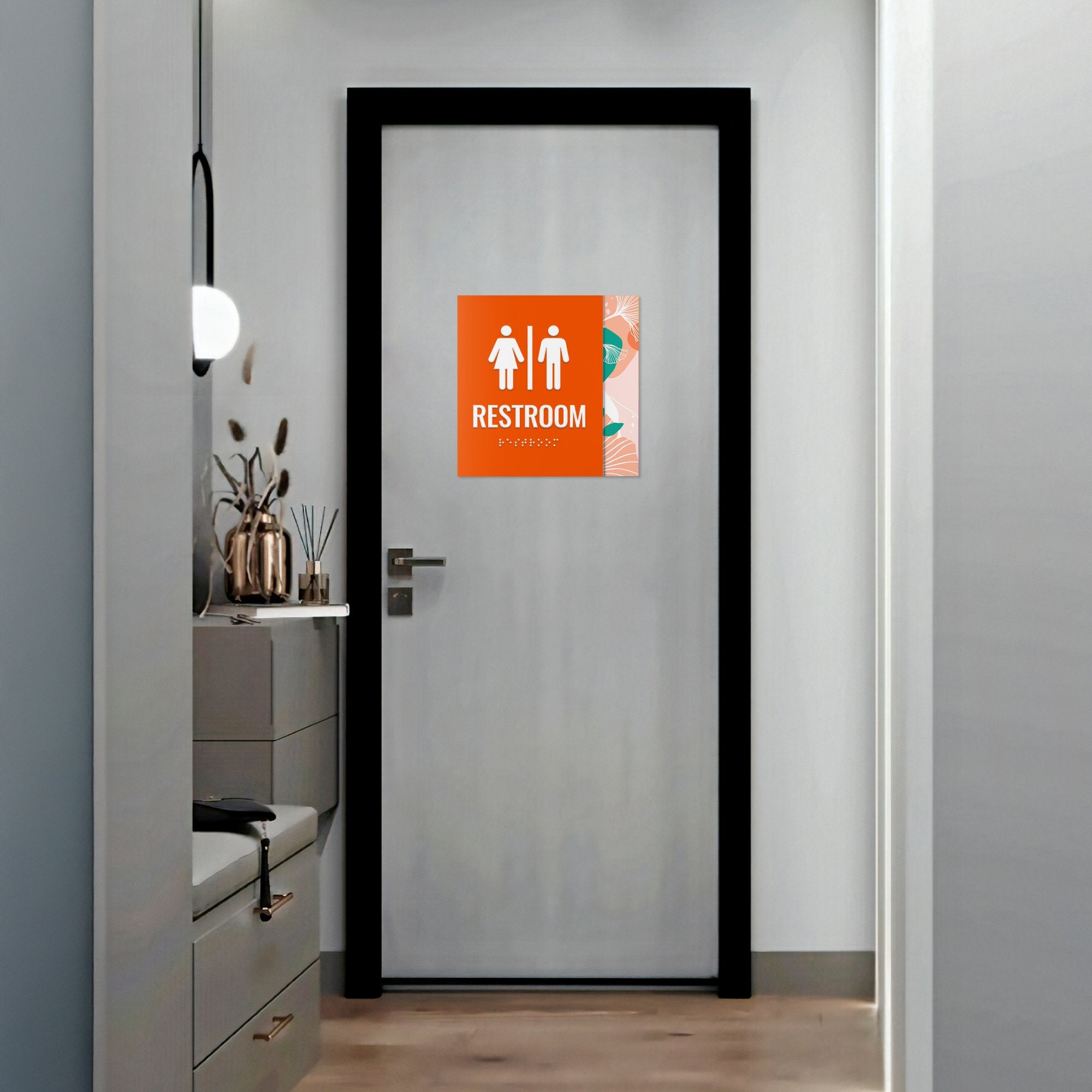 A large 2-layered ADA sign with an orange foreground and floral background for a restroom A large 2-layered ADA sign with an orange foreground and floral background for a restroom