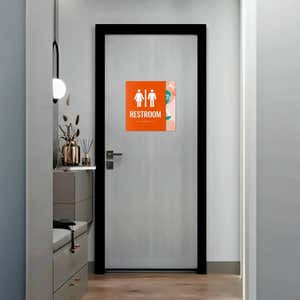 A large 2-layered ADA sign with an orange foreground and floral background for a restroom