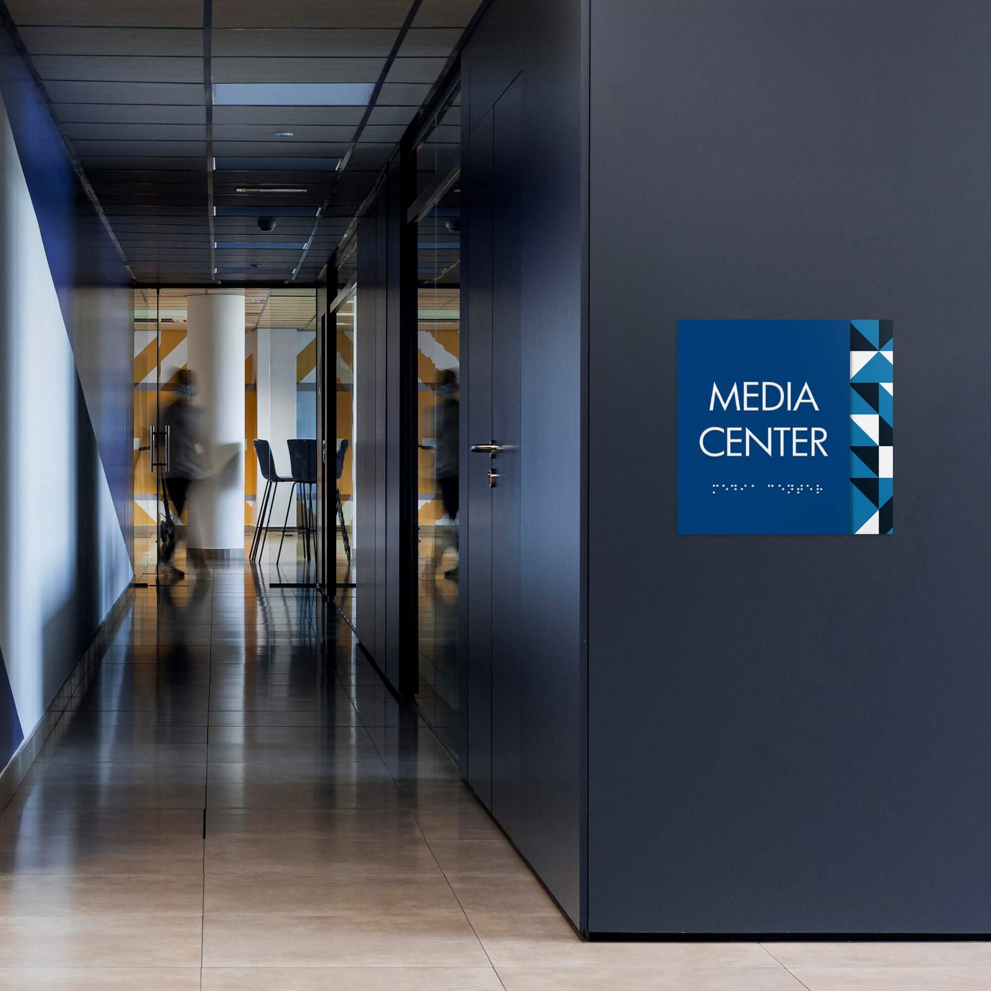 A large layered ADA sign for a media center with a blue foreground and blue geometric background A large layered ADA sign for a media center with a blue foreground and blue geometric background