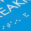 A close-up on the braille and tactile text on the ADA sign