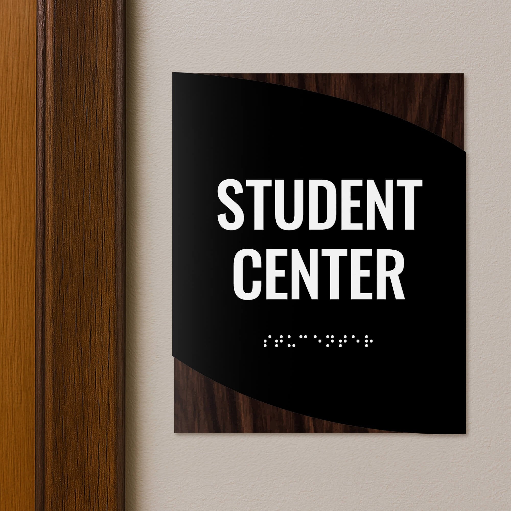 A modern twist design ADA sign for a student center with the dark wood background and black foreground