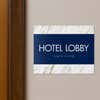 A 2-layered horizontal ADA sign for a hotel lobby with a blue foreground and white marble background