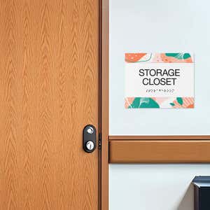 The horizontal 2-layer ADA sign for a storage closet with a white foreground and orange floral background