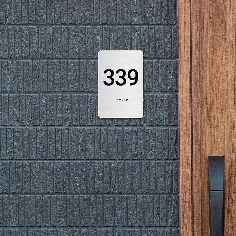 A gray ADA sign with a room number