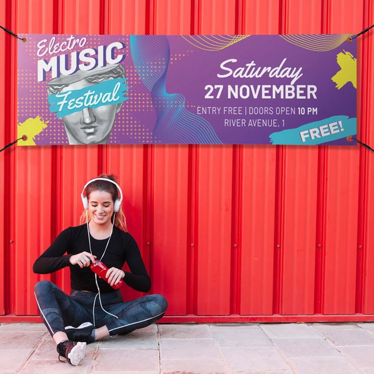 Purple outdoor vinyl banner with bold event typography and graphic design elements, mounted on a red corrugated wall