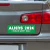 Aliens - Humans Aren't Real Bumper Sticker below a gray car's tail light