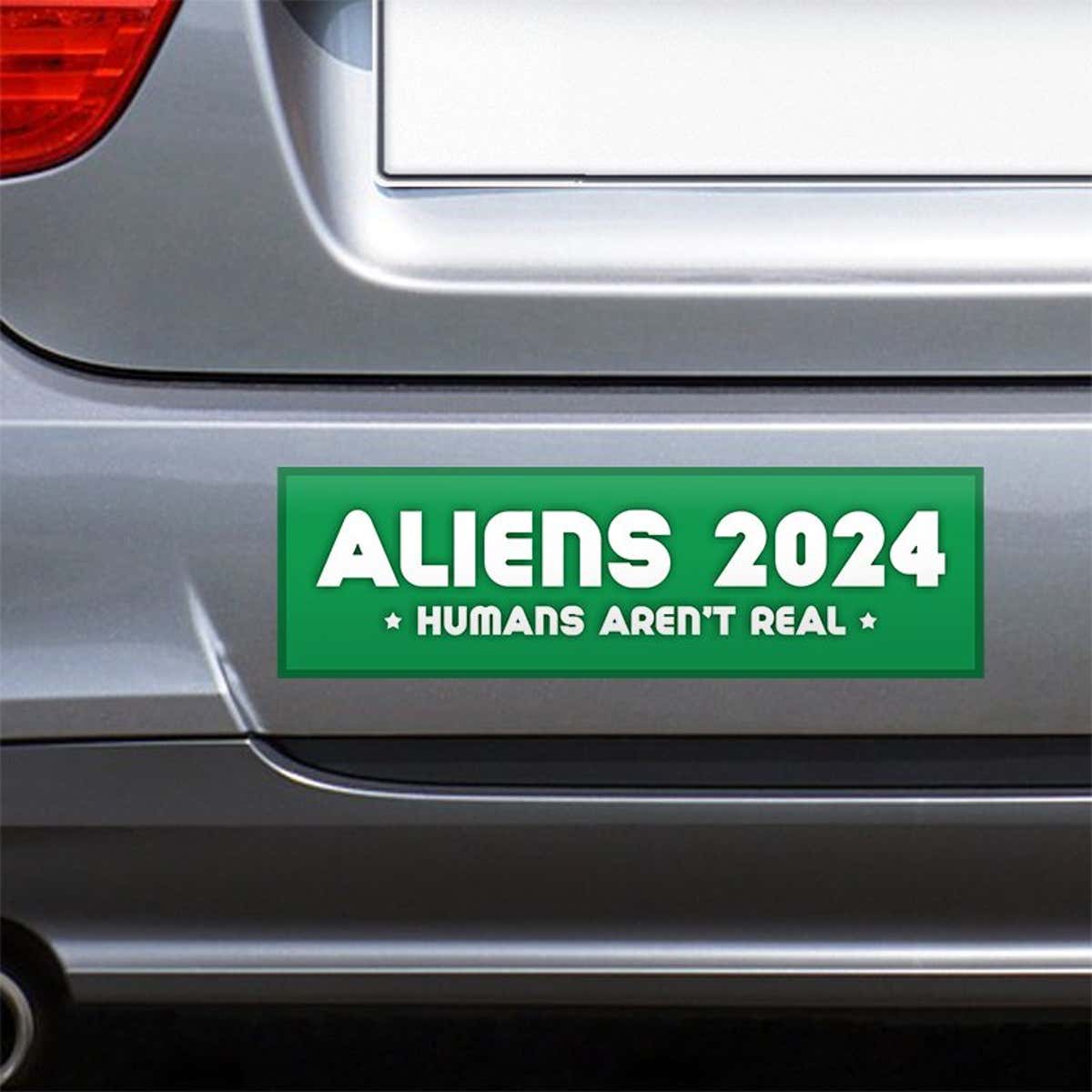Aliens - Humans Aren't Real Bumper Sticker on the bumper of a gray car