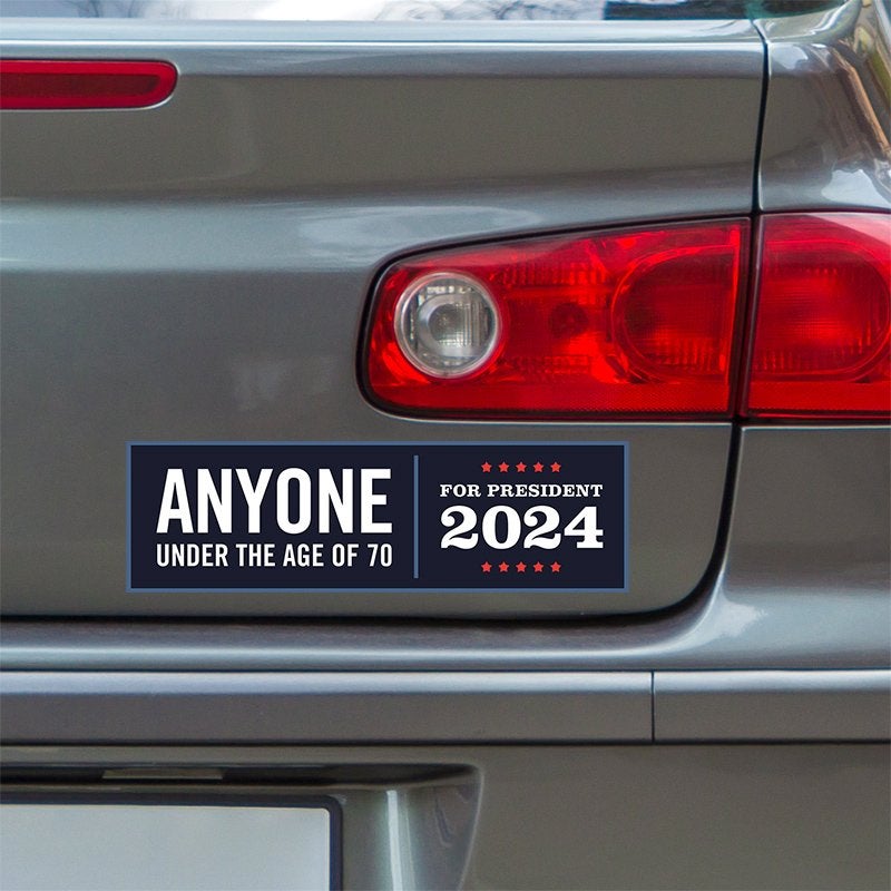 Anyone Under 70 bumper sticker below a gray car's tail light