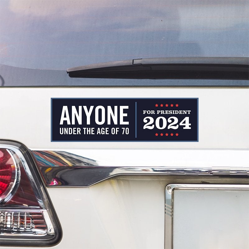 Anyone Under 70 bumper sticker above a white car's tail light