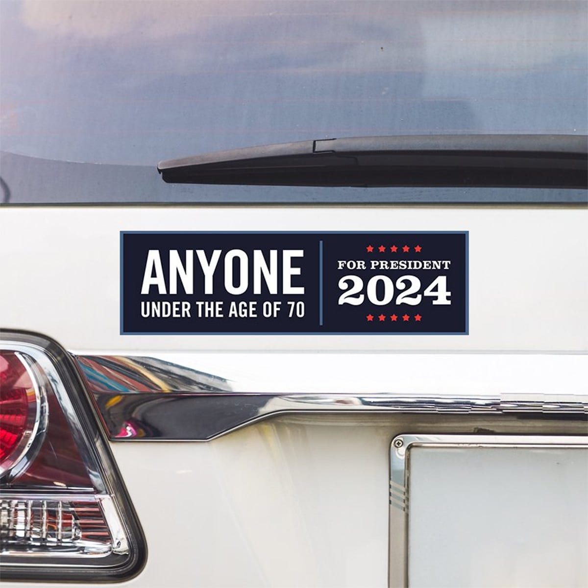 Anyone Under 70 bumper sticker above a white car's tail light