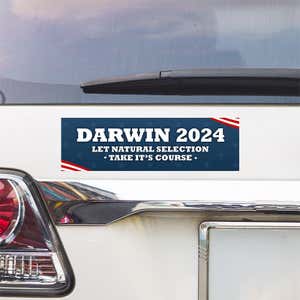 Darwin Political Bumper Sticker above a white car's tail light