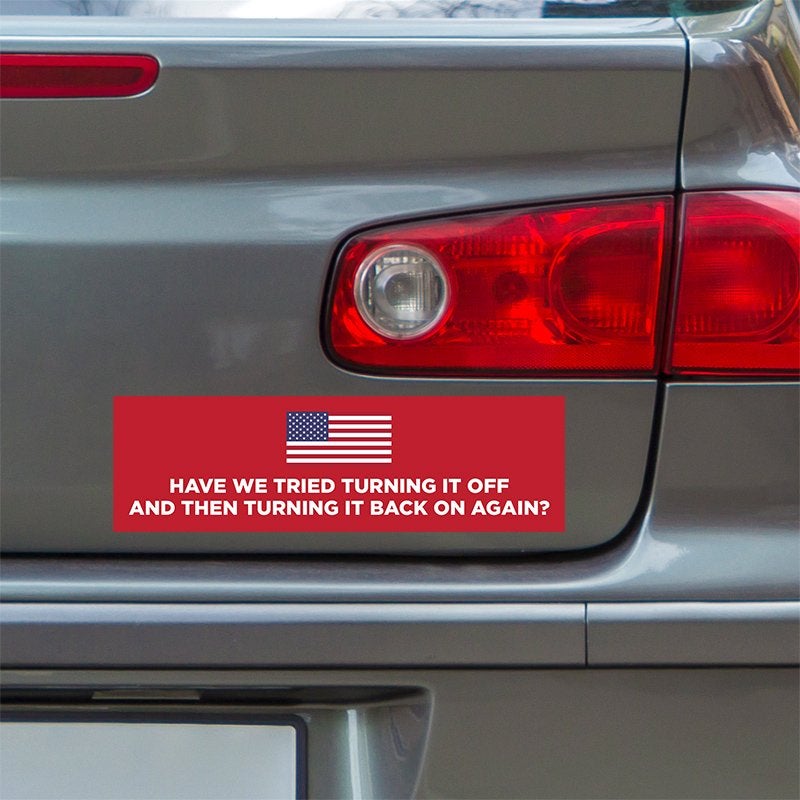 American Flag Funny Political Bumper Sticker below a gray car's tail light