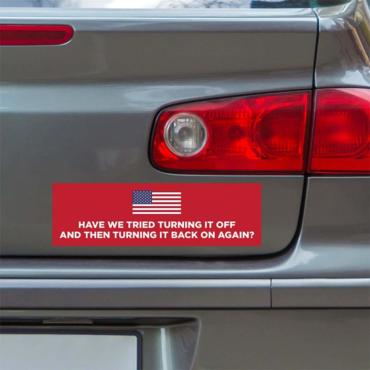 American Flag Funny Political Bumper Sticker below a gray car's tail light