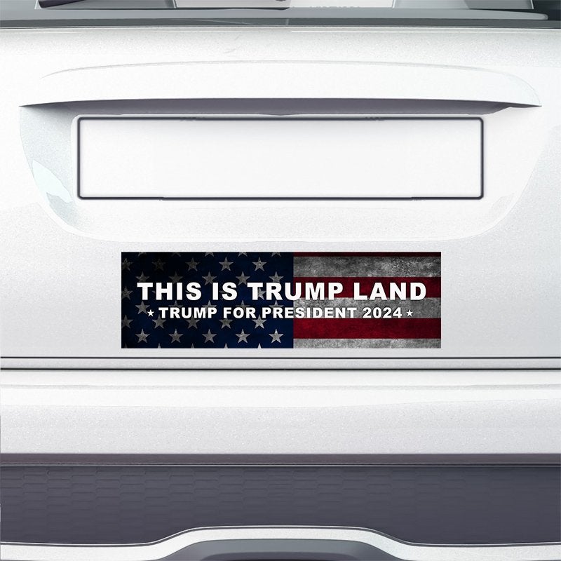 This is Trump Land Bumper Sticker on the bumper of a white car