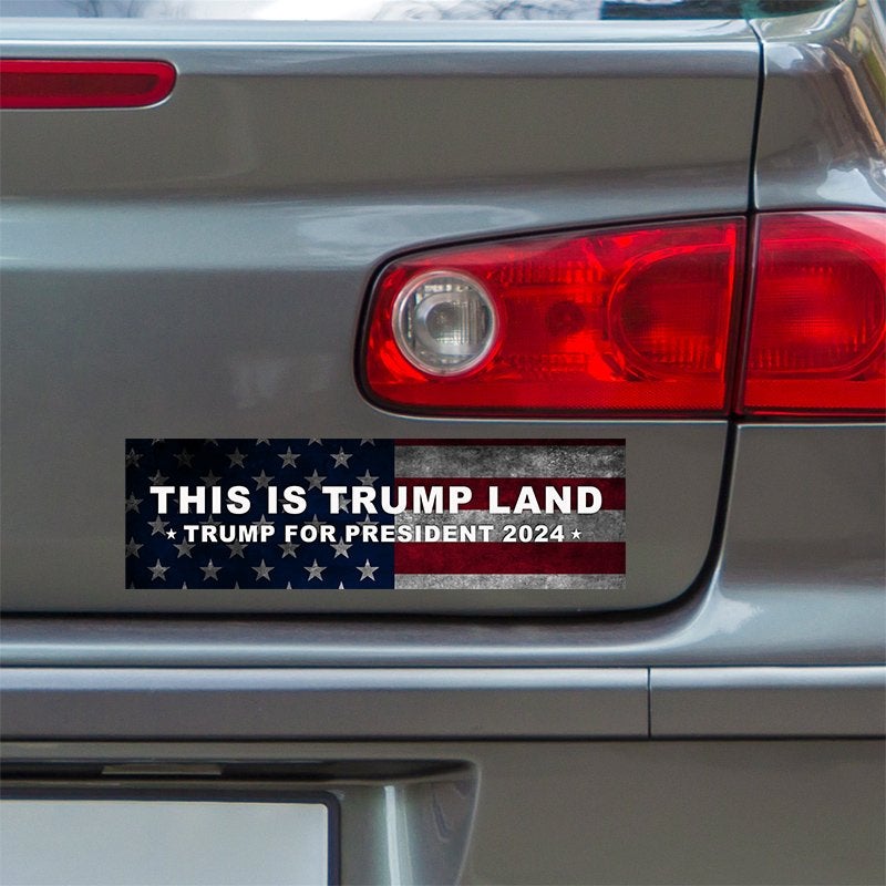 This is Trump Land Bumper Sticker below a gray car's tail light