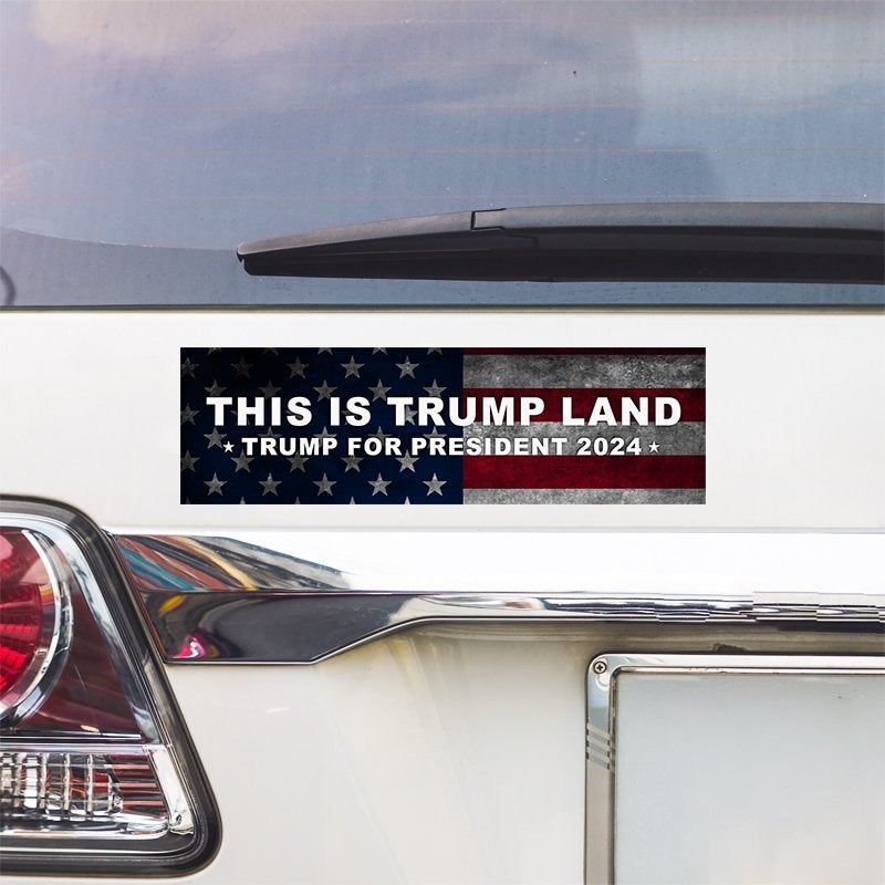 This is Trump Land Bumper Sticker above a white car's tail light