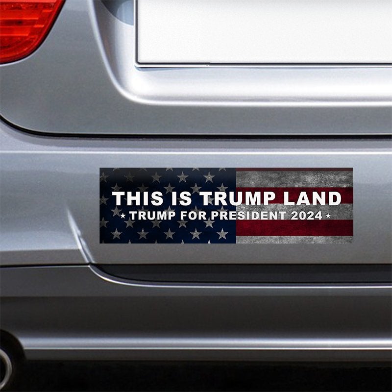 This is Trump Land Bumper Sticker on the bumper of a gray car