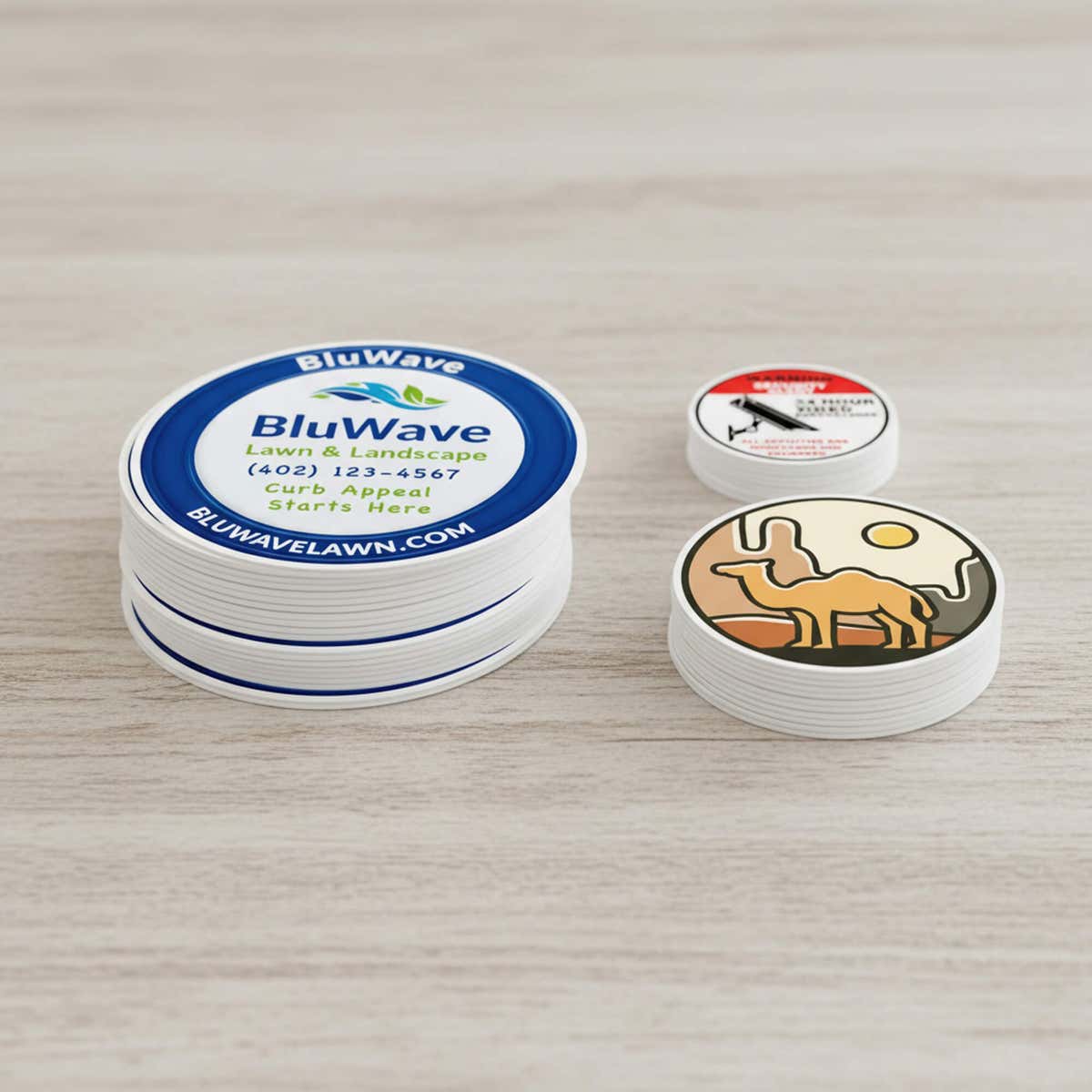 Three stacks of different custom vinyl sticker designs in varying sizes