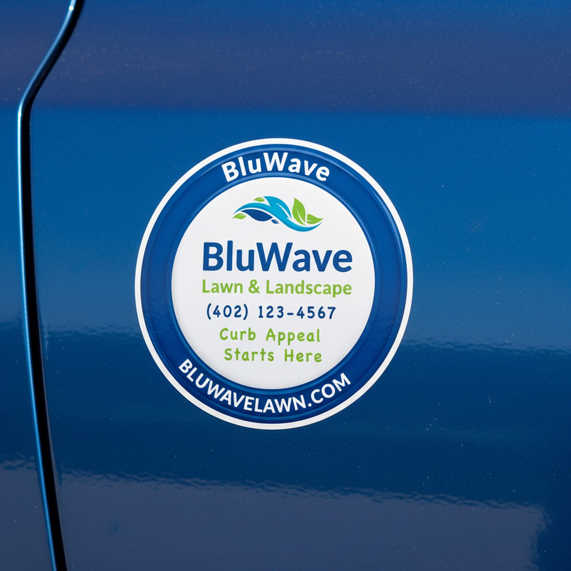 A round vinyl sticker for a lawn and landscaping company on a blue car