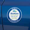 A round vinyl sticker for a lawn and landscaping company on a blue car