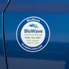 A round vinyl sticker for a lawn and landscaping company on a blue car