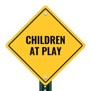 A yellow diamond sign on a post with the message CHILDREN AT PLAY