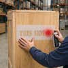 A person spray painting onto a wooden box using a stencil