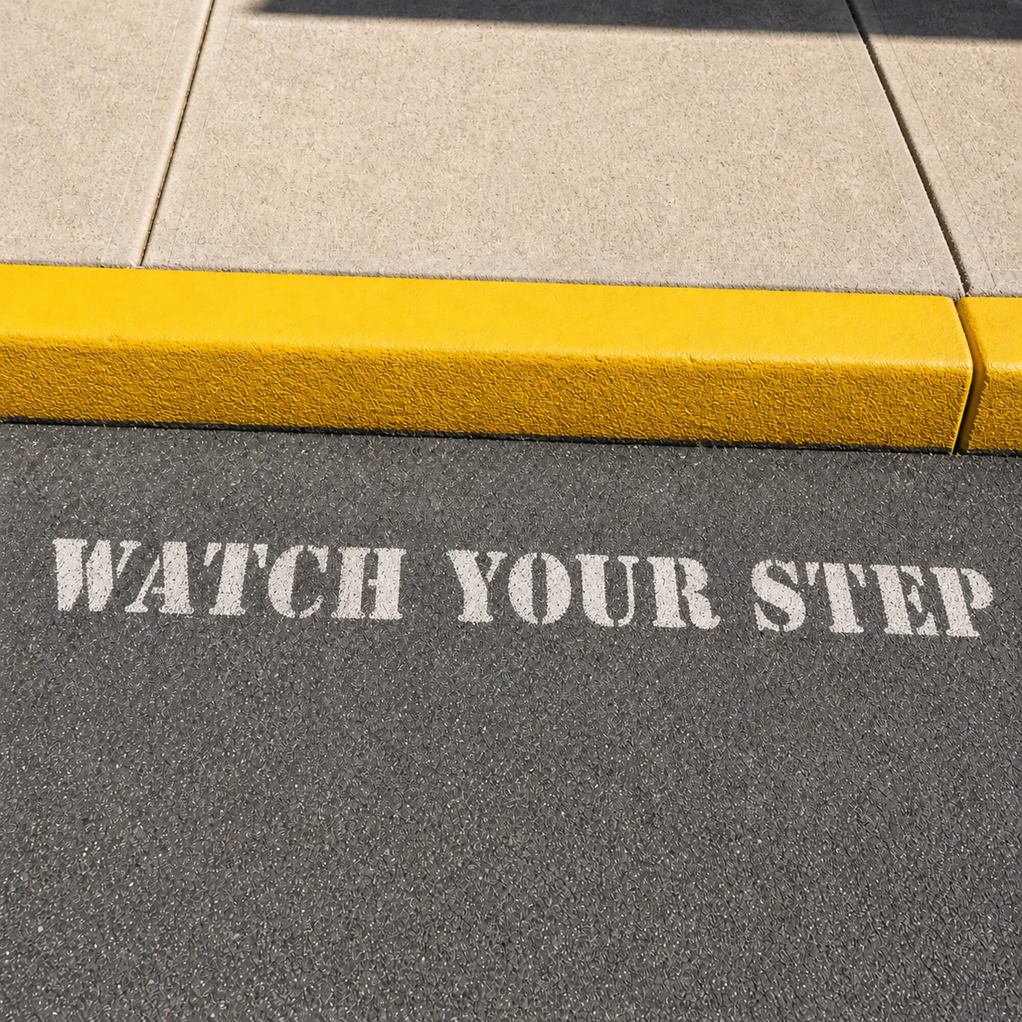 Watch Your Step sprayed onto a sidewalk using a stencil Watch Your Step sprayed onto a sidewalk using a stencil