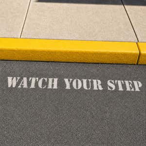 Watch Your Step sprayed onto a sidewalk using a stencil