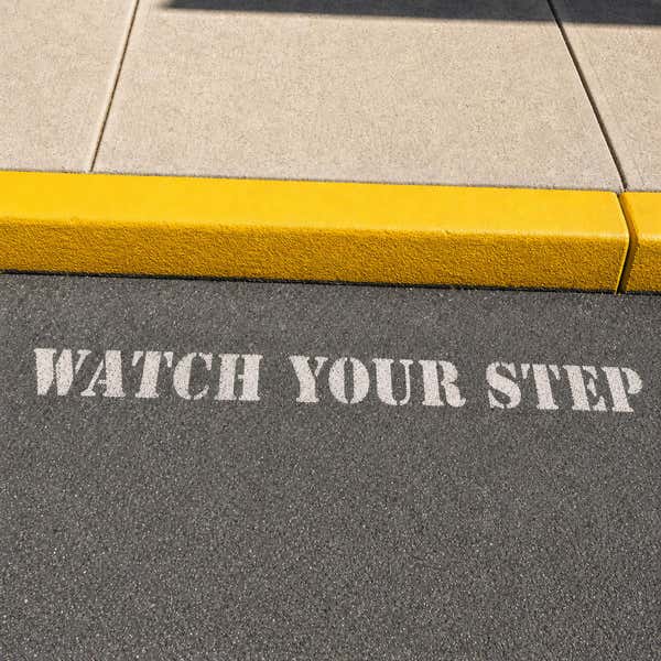 Watch Your Step sprayed onto a sidewalk using a stencil