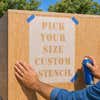 A man using the custom size stencil on a wooden box