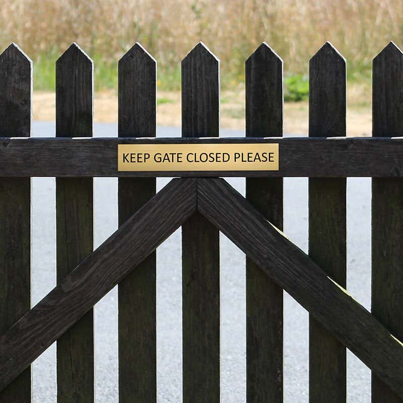 2x12 custom engraved brass sign on a fence