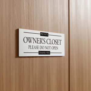 A small plastic sign on a door to label a private closet 