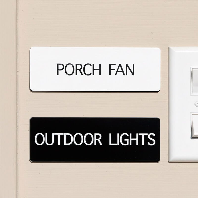 White and black engraved plastic signs being used to label and porch fan and outdoor lights
