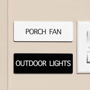 White and black engraved plastic signs being used to label and porch fan and outdoor lights