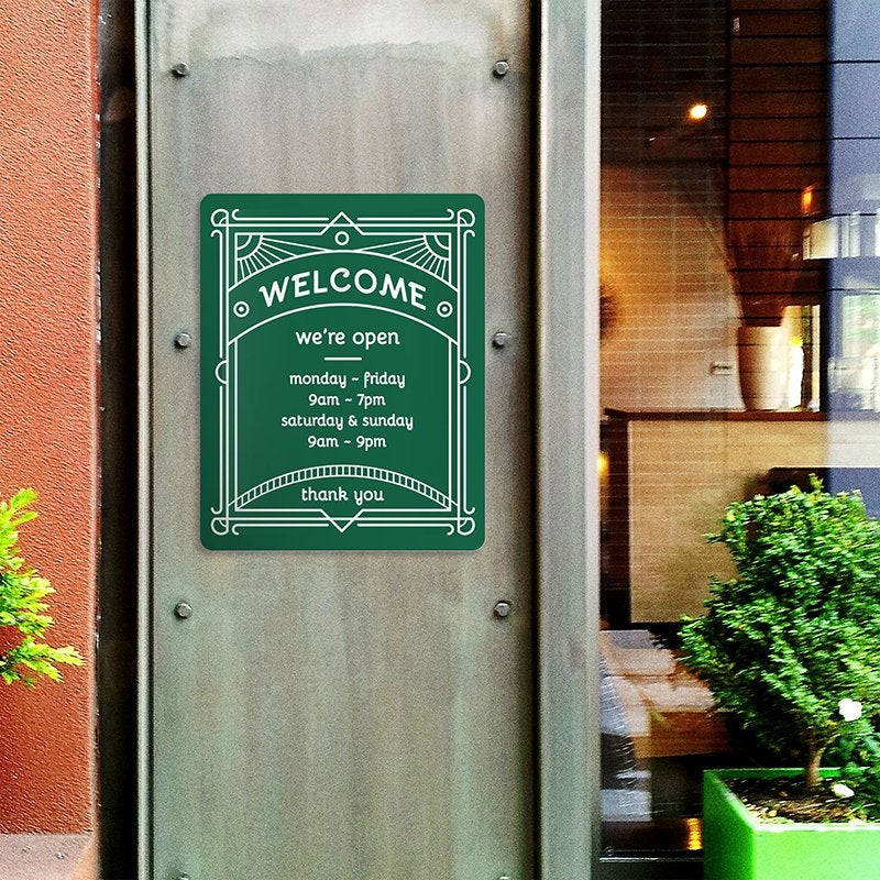 A green engraved plastic sign with a store's business hours A green engraved plastic sign with a store's business hours