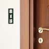 A green engraved plastic sign with a room number