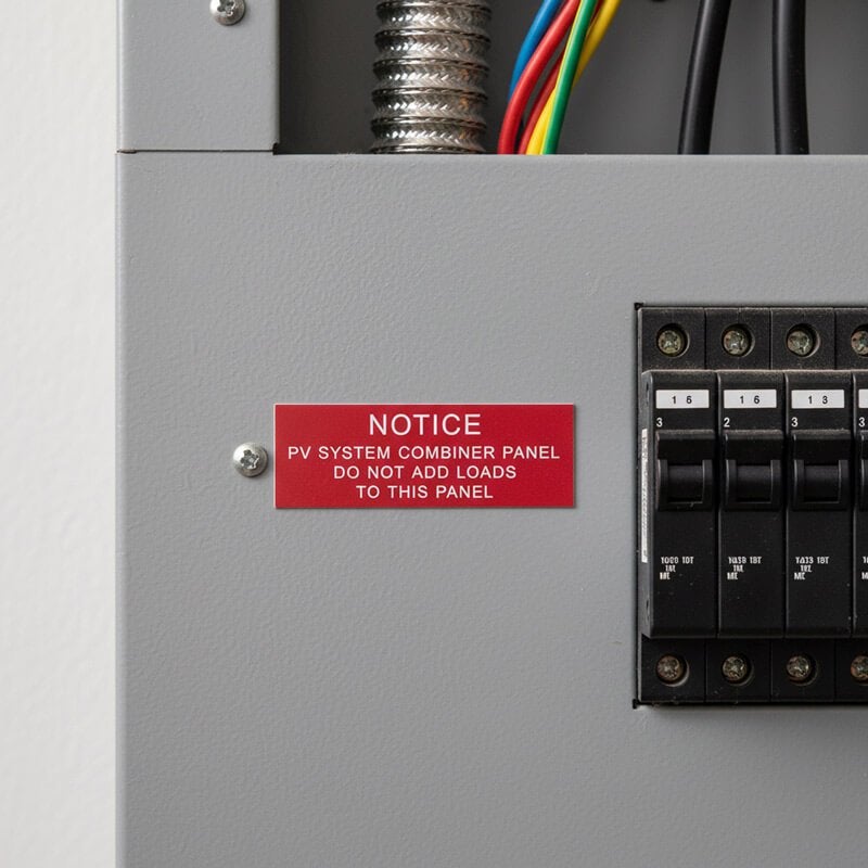 A red engraved plastic sign next to a panel to give a notice