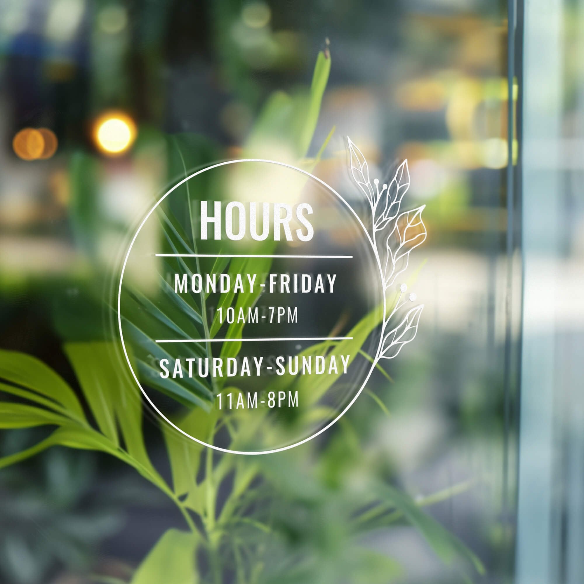 Round business hours decal on a window with greenery behind it
