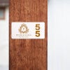 A room number sign with the hotel logo next to the number