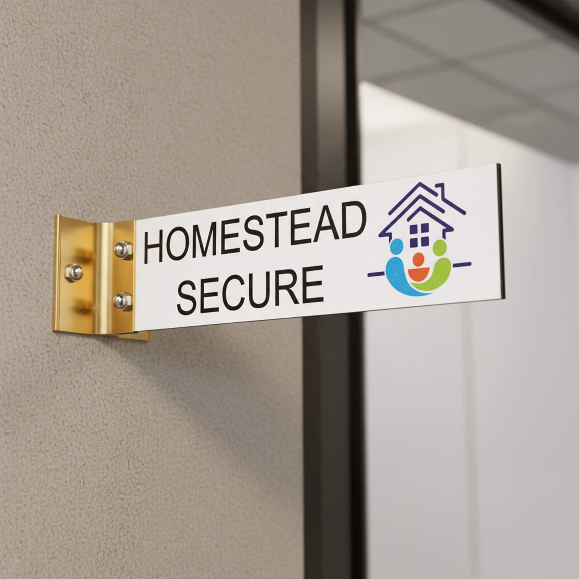 2” x 8” Corridor sign with white material color, black engraved text, logo, and gold holder on a hallway wall with custom text saying “HOMESTEAD SECURE”.