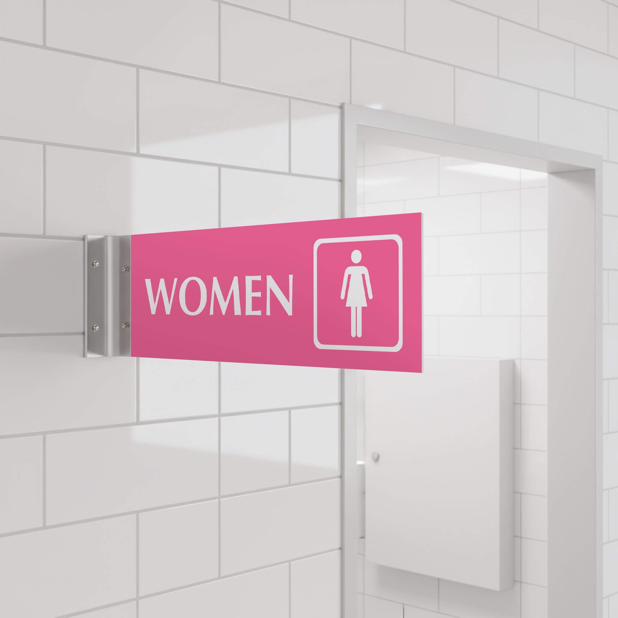4” x 12” Corridor sign with pink material color, white engraved text, logo and silver holder on a hallway wall with text saying “WOMEN”.