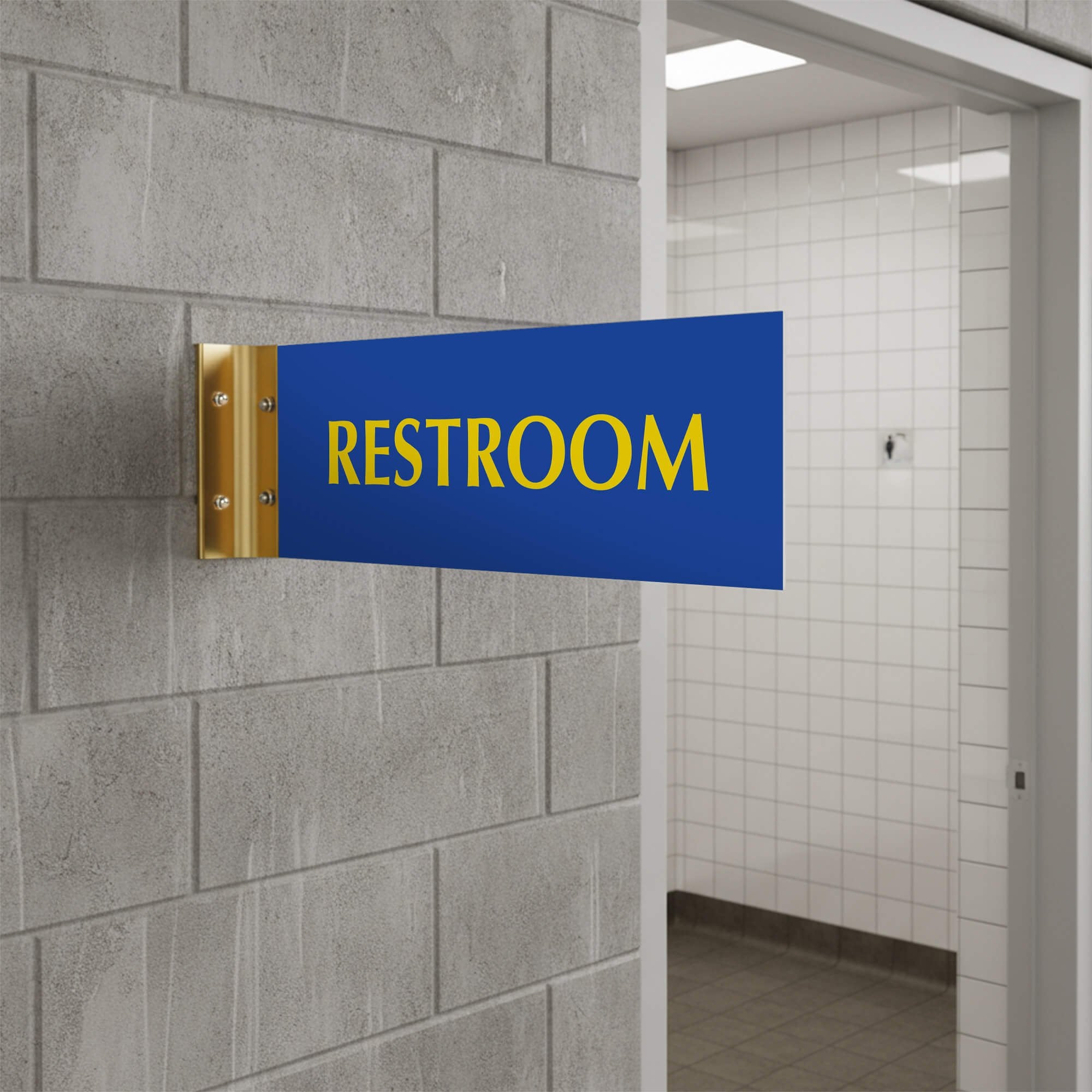 4” x 12” Corridor sign with blue material color, yellow engraved text, and gold holder on a hallway wall with text saying “RESTROOM”.