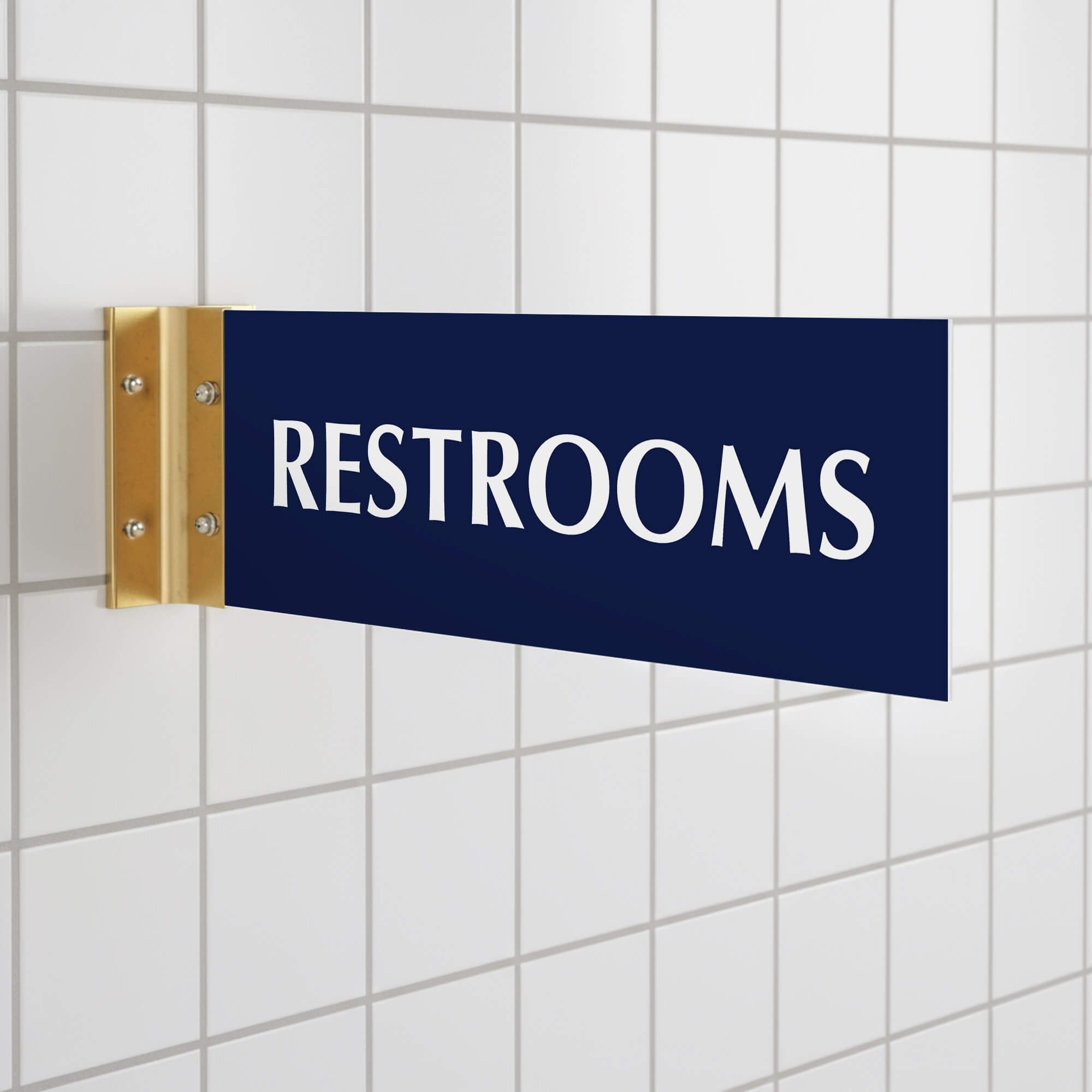 4” x 12” Corridor sign with blue material color, white engraved text, and gold holder on a hallway wall with text saying “RESTROOMS”.